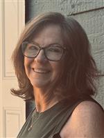 Photo of Leslie Mcshane wearing a green tank top and wearing glasses.